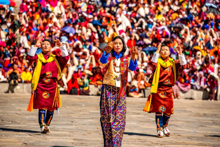 Three folk dancers in traditional dress performing in front of a festival crowd